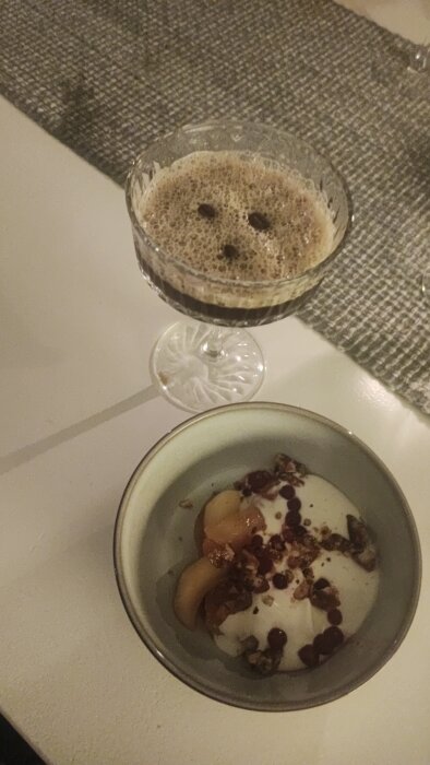 Espresso martini med sprucket skum och en dessert av äpplen, vaniljkräm, hasselnötsknäcke och lingon i en skål.