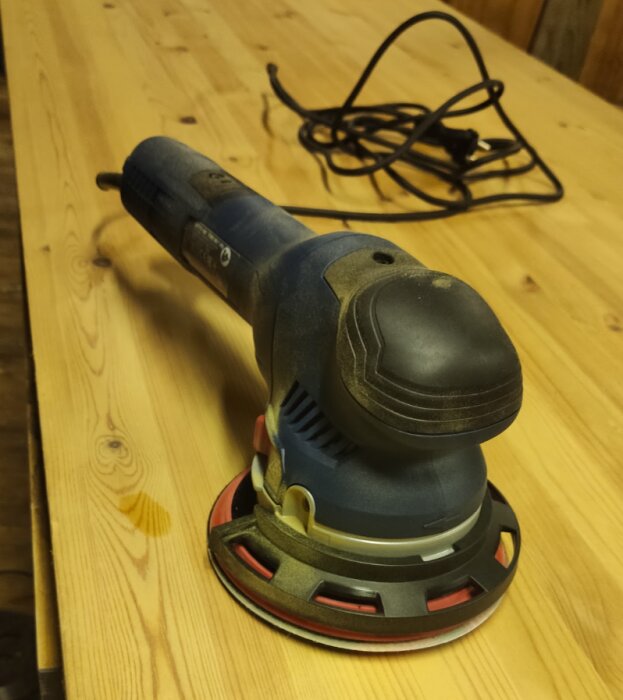 Blå Bosch slipmaskin på träbord, nystartat projekt i verkstaden.