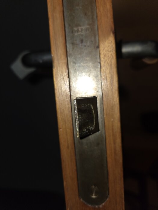 En närbild på en innerdörrs lås av äldre modell, märkt med "ASSA", där problemet beskrivs som svårt att stänga och låsa dörren.