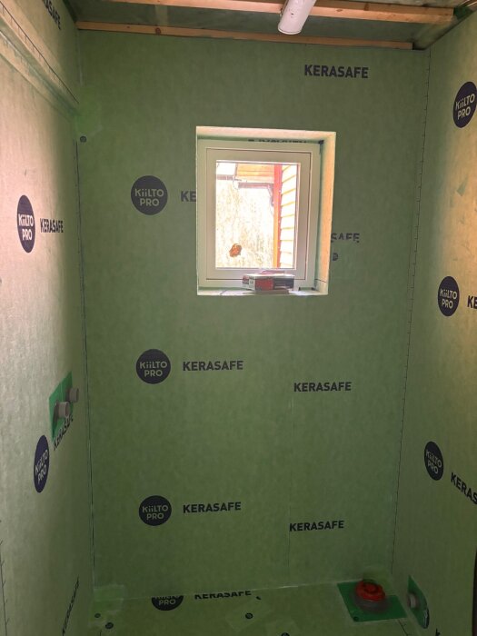 Badrumsvägg med KiiltoPro och Kerasafe tätskikt, fönster centrerat på väggen. Förberedelse för kakelinstallation syns runt fönster och väggar.