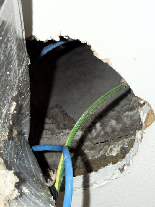 Hål i väggen med synliga kablar, del av en diskussion om pluggning av gammal ventilationskanal från badrumsrenovering i 70-talshus.
