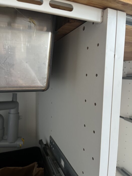 Köksstomme under diskbänk med rörliga delar och inga synliga skruvar, misstänkt lim.