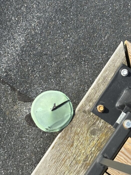 Grön ventilationshuv med snitt på papptak bredvid trädel och svarta metallbeslag.