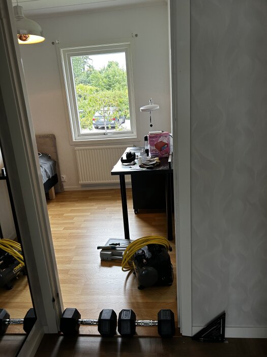 En fönsterram med foder efter renovering, med verktyg och hantel på golvet i ett rum.