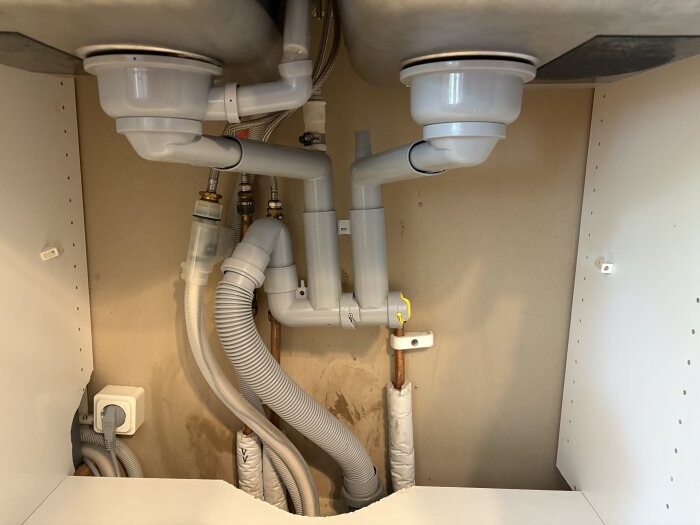 Rörsystem under diskho med flera anslutningar och slangar för avloppsvatten, visar potentiella orsaker till långsam avrinning.
