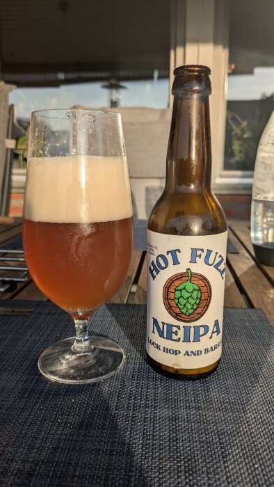 Flaska och glas med öl på ett bord, etikett på flaskan "Hot Fuzz NEIPA".