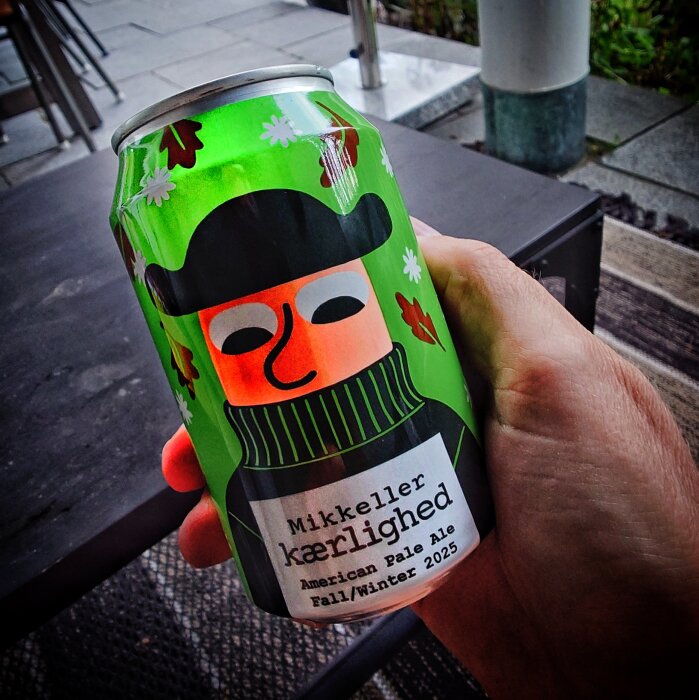 Konservburk med etikett "Mikkeller kærlighed American Pale Ale Fall/Winter 2025", hålls i en hand.