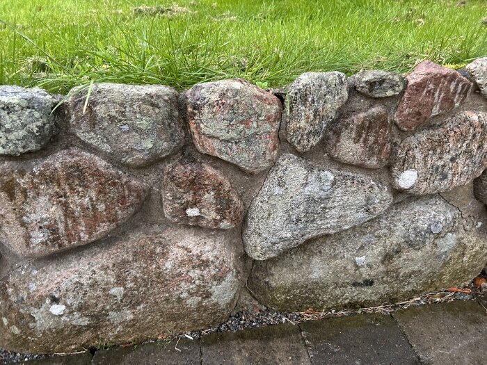 Stenmur med olika stora stenar i nära anslutning till gräs. Muren är ett byggprojekt och användaren söker tips om murbruk.