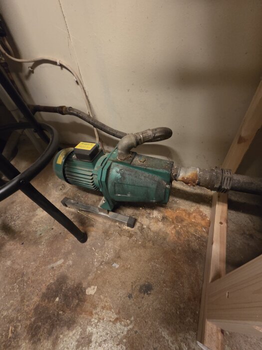 Grön laddomat med röranslutningar på ett betonggolv inomhus.