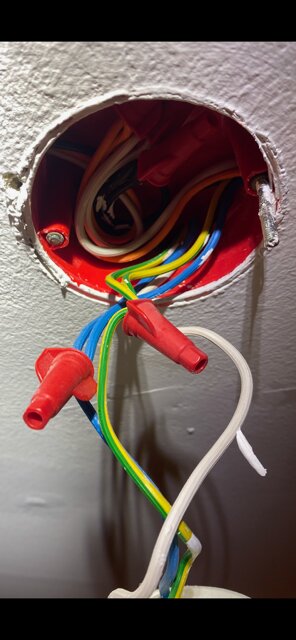 En elbox i taket med flera synliga kablar och röda plastkontakter, en skruv av och den andra svår att lossa.