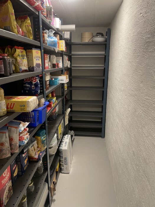 Hyllor i en matkällare fyllda med matvaror och hushållsartiklar, ombyggda för att passa utrymmet.