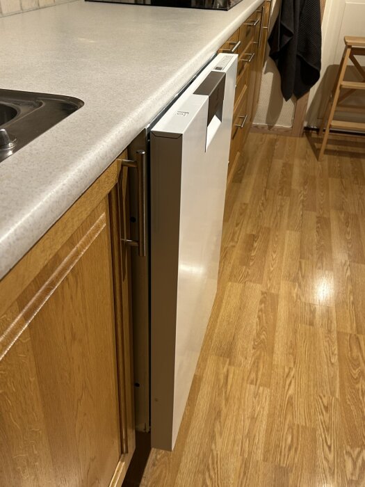 Diskmaskin utdragen på köksgolvet med luckan i linje med bänkskivan.