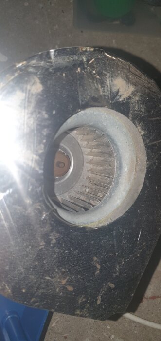 Fläktblad och motor i en trasig Separett Villa 9000 komposttoalett, delvis täckt av damm och smuts.