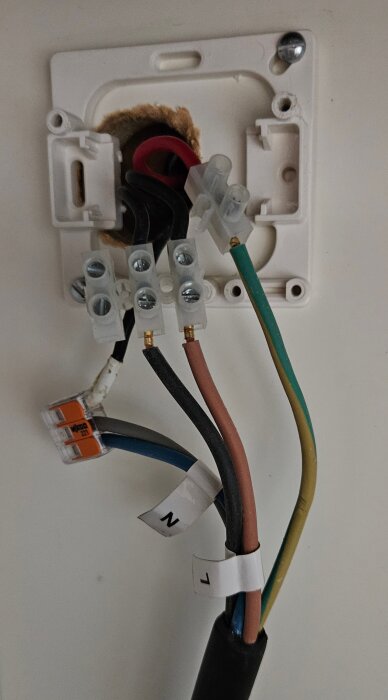 Trasig kopplingsdosa med synliga kablar och provisoriska lösningar för spishäll, visar flera ledningar inkopplade i plast- och wago-kopplingar.
