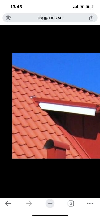 Rött tegeltak med plåtskarv där ett mindre tak ansluter till ett större tak, tydlig blå himmel i bakgrunden.