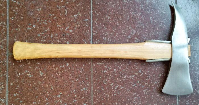 Brandyxa från en nedlagd yxfabrik i Säter, liggande på rödbrun klinkerplatta.