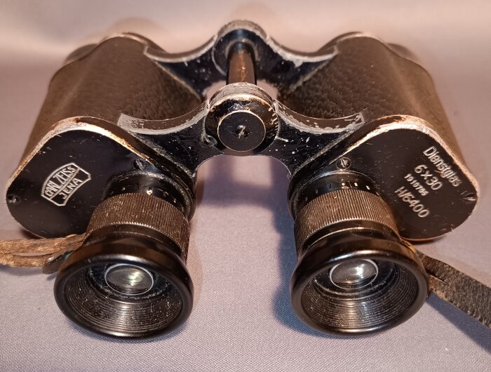 Gammal kikare av märket Carl Zeiss Jena, modell 6x30, med slitage och bortslipade stämplar, placerad på enfärgad yta.