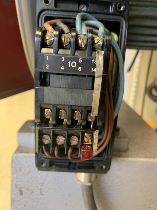 Närbild på en elektrisk plint med flera skruvanslutningar och kablar, relaterad till diskussion om en silverfärgad Lini med motorskydd.