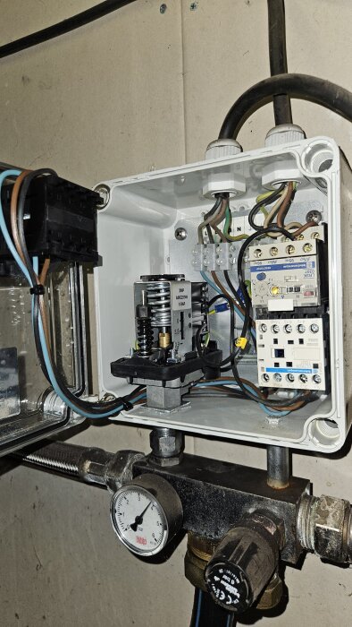 Elskåp med tryckvakt och elektroniska komponenter, del av dränkpumpinstallation, synligt tryckmätare visar cirka 2 bar.