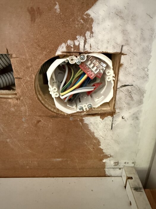 Felmonterad dosa för eluttag i kök, synlig kablar och osläta kanter, visar problem med ram och montering. Vänsterjusterad och sned position.