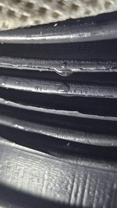 Närbild på ett sprucket flexrör för avloppsavluftning med kondensdroppar på ytan.