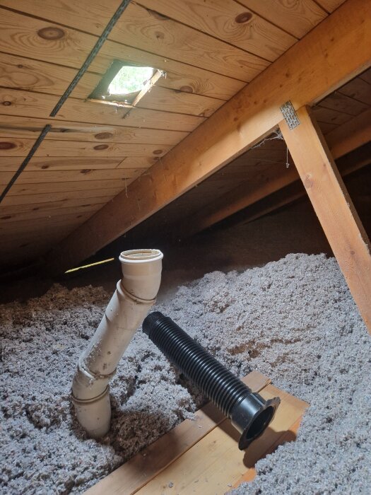Flexrör och PVC-rör i en vind med isolering och takbjälkar, hål i taket syns ovanför.
