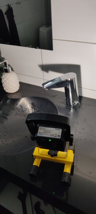 IR-vattenkran installerad vid ett handfat, belyst av en batteridriven handlampa placerad på bänkskivan.