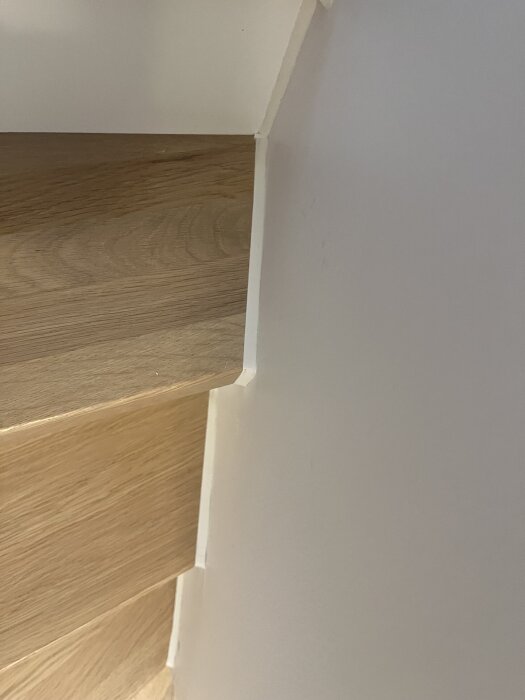 Trätrappa med ljus vägg, noggrant rengjord, visar resultat efter användning av ett effektivt städknep från Bauhaus.