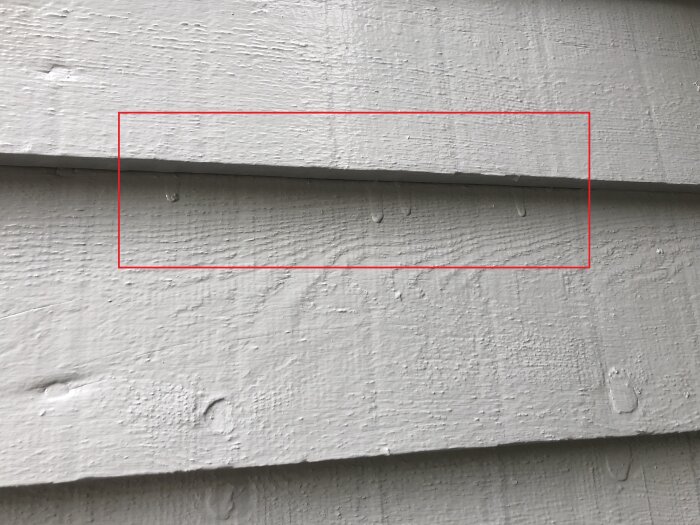Färg som runnit ner på villans liggande brädor, vilket visar mindre korrekt målningsarbete. Röd rektangel markerar område med färgfel.
