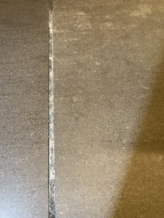 Klinkergolv med fog där vita fläckar liknar pulver, potentiellt tecken på fuktskada nära badrumsdörr.