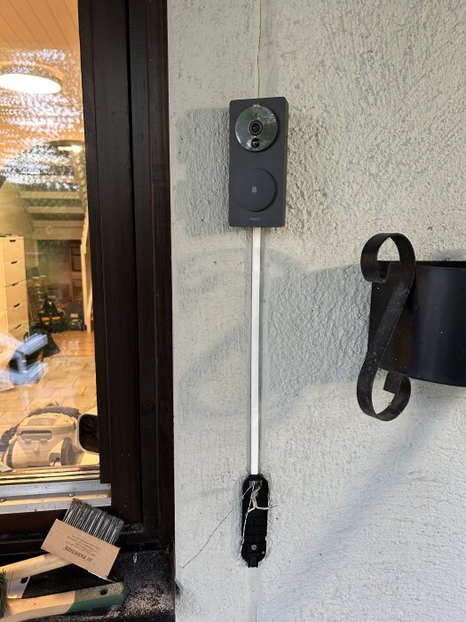 Aqara G4 videodörrklocka monterad på en ljus husvägg med synlig kabeldragning och del av ett fönster till vänster.