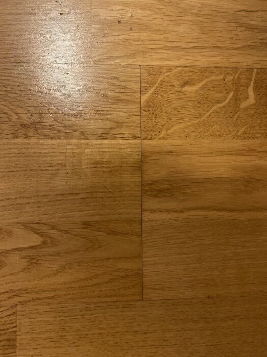 Ljusa träplankor med svarta linjer emellan, kan indikera potentiell fuktskada eller mögeltillväxt under golvet.