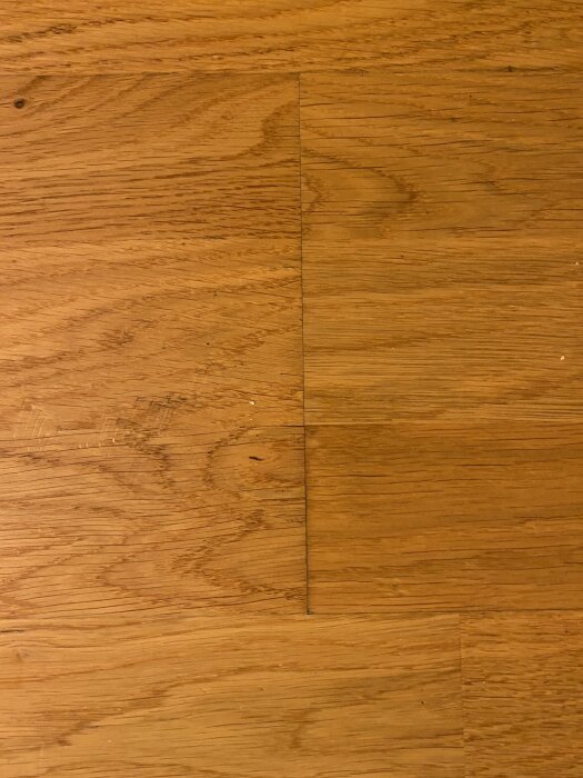 Trägolv med glipor mellan plankorna, möjligt tecken på fukt eller mögel.