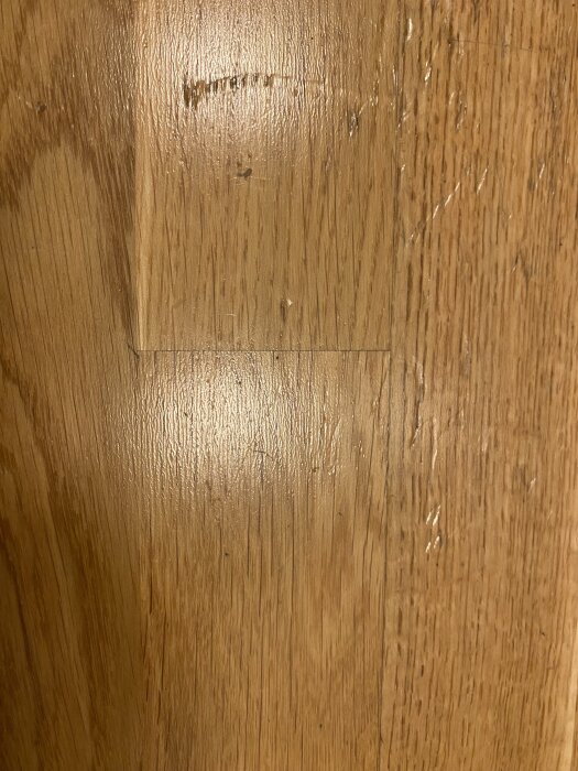 Bild på ett golv med djupa hack och en glansig yta som ser plastig ut, ifrågasätts om det verkligen är parkettgolv.