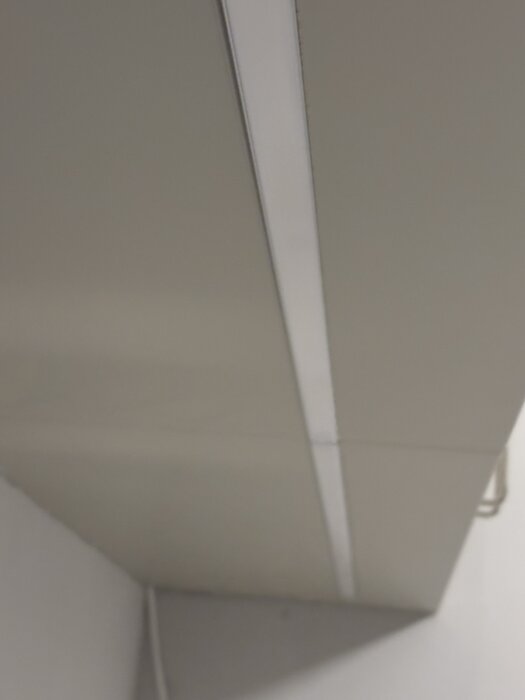 Glipa mellan täckskiva och kökslampa i Ikeakök, ojämn skarv och slarvigt sågade kanter.