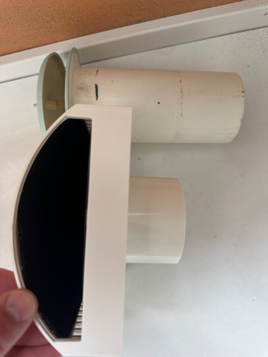 Ventilationsdelar jämförs, inklusive en vit ventiladapter och ett rör, med tanke på att matcha olika storlekar och täckning av isolering.