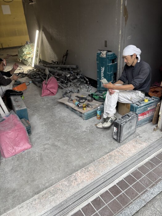 Byggverkstad i centrala Tokyo; man i bandana använder Makita-verktyg, belysning och byggmaterial i bakgrund.