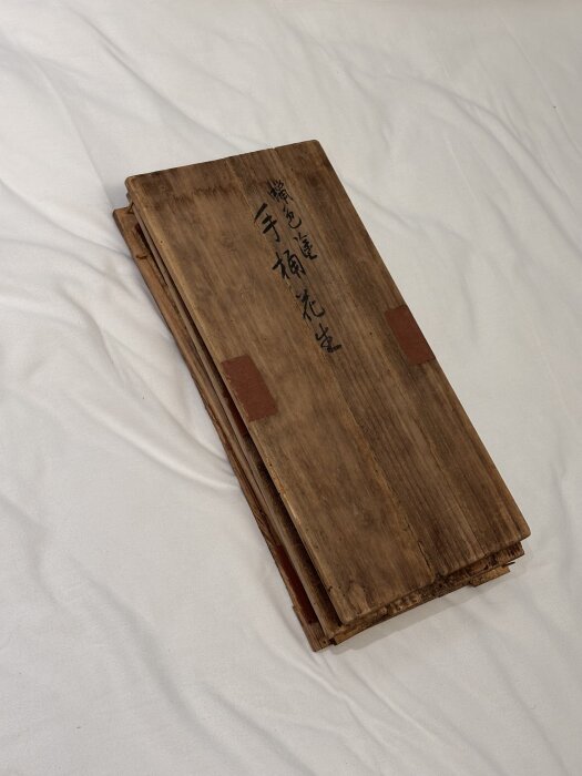 Träplankor med asiatisk text staplade på varandra, del av återbrukat material från en låda till en Ikea-möbel.