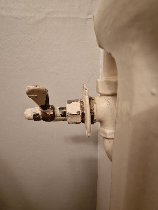 Gammal slottsventil på ett element med utslitna beslag och avskalad färg, del av diskussion om ventilbyte till termostatmodeller.