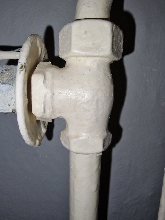 Radiatorventil med invändig gänga i metallrör, målad vit.