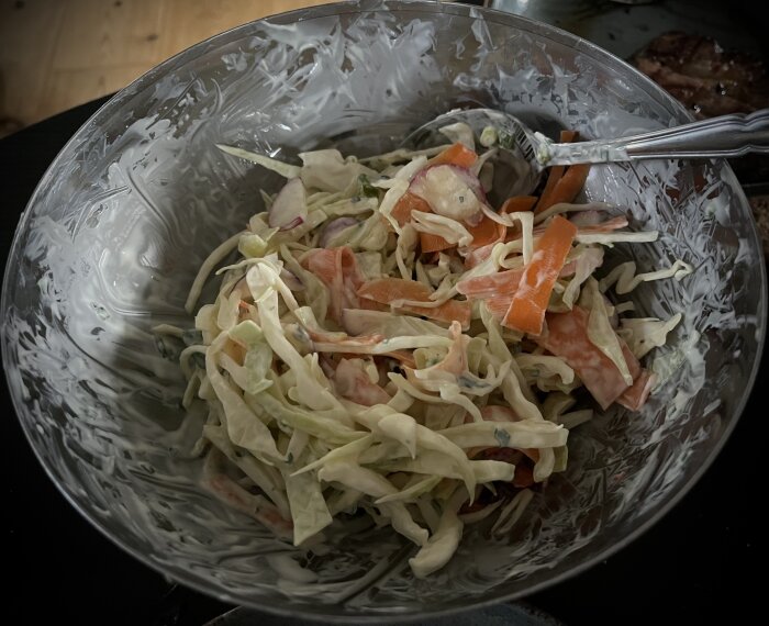 Hemlagad kålsallad med strimlad vitkål, morötter, rädisor och salladslök, blandad med majonnäs och yoghurt i en skål.