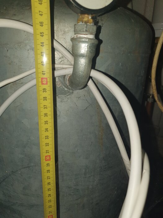 Hydrofor med ansluten ledning och måttband som visar höjd.