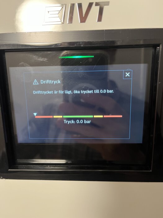 Bild av en skärm som visar ett meddelande om lågt drifttryck och instruktionen "öka trycket till 0.0 bar". Fyra färgade staplar indikerar trycknivå.