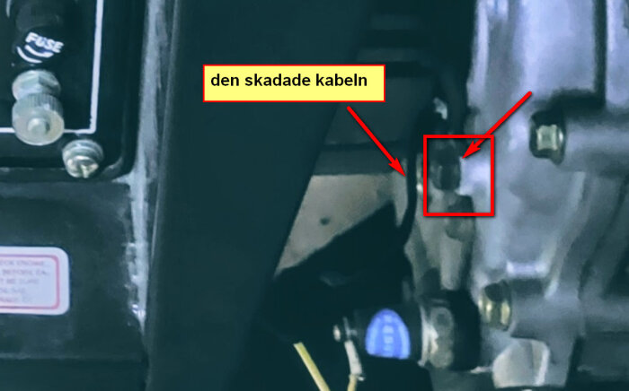 Skadad svart kabel på ett motorblock med pilar som pekar mot skruvanslutningen.
