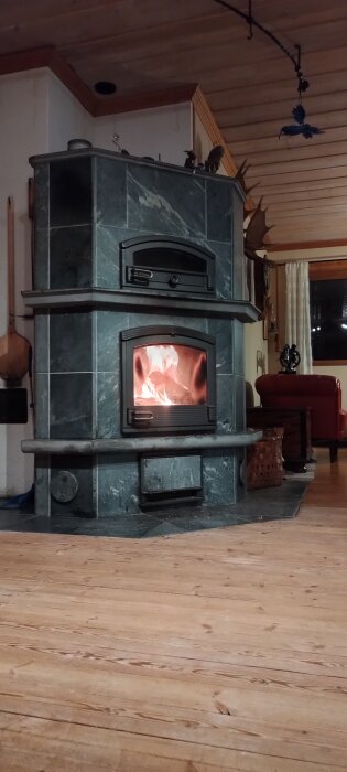 Eldstad i sten med brasa inuti, hemtrevlig atmosfär i ett rum med trägolv och väggar.