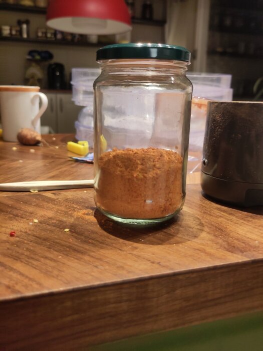 Burk med hemmagjort chilipulver från 1,5 liter jalapeños på ett köksbord.