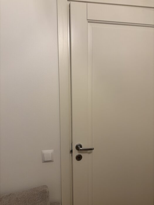 Dörr med handtag, ses med mellanrum mot karmen vid handtaget, indikerar problem med passform i en bostadsrätt byggd 2017.