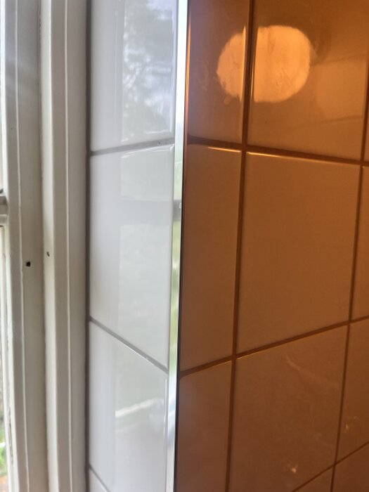 Vitt kakel med alulist till vänster och orange kakel utan list till höger.