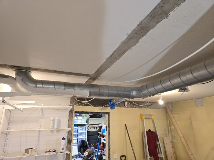 Ventilationsrör i taket på ett renoveringsprojekt, med verktyg och material i bakgrunden.