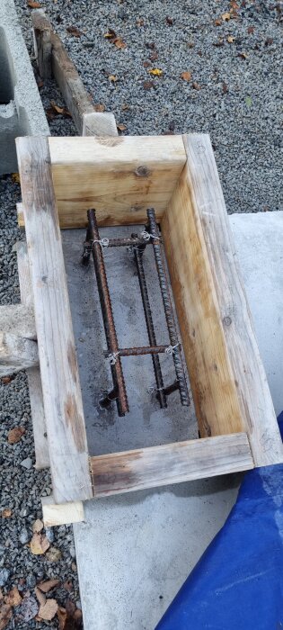 Armering med träform för gjutning av sockel i mindre stallprojekt, sikt uppifrån på grov mark, omgiven av lecablock och stenar.